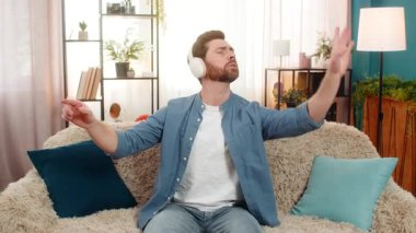 Evde kulaklık takan genç adam, orkestra yönetir gibi el kaldırıyor, müzikten tamamen keyif alıyor. Kanepede oturan beyaz adam ritmik hareket eder, melodide kaybolur, tutkuyu ve yaratıcılığı ifade eder.