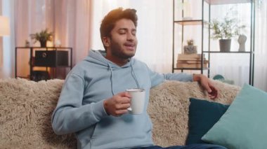 Gülümseyen Hintli adam evde sıcak kahve ya da bitki çayı içiyor. İspanyol adam moladan zevk alıyor, sabahları kanepede oturuyor, düşünceli bir şekilde uzaktan bakıyor ve dinleniyor..