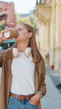 Kafkasyalı mutlu kadın sabah kahvesinin tadını çıkarıyor sıcak içecek ve gülümsüyor. Dinleniyorum, ara veriyorum. Şehir merkezi caddesinde yürüyen genç bir kız, gitmek için kahve içiyor. Dışarıdaki kasaba yaşam tarzları.