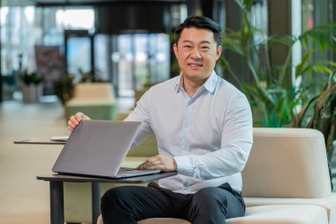 Çinli genç iş adamı otel lobisindeki işi bitirdikten sonra dizüstü bilgisayarı kapatıyor. Gülümseyen yönetici internette çalışıyor, uzaktan kumandayla. E-öğrenme, internette gezinme, netbook 'ta kameraya bakma..