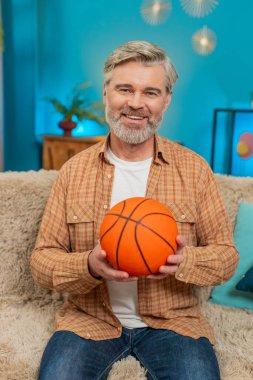 Olgun bir adam evinde rahat bir koltukta oturuyor, elinde bir basketbol topu tutuyor ve fırlatıyor. Orta yaşlı adam topu parmağında döndürüyor, hafif hissediyor, neşeli anın tadını çıkarıyor. Oyun rahatlama mutluluğunun keyfi. Dikey