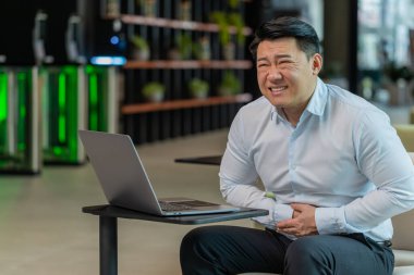 İş sırasında ofis lobisindeki dizüstü bilgisayarda aşırı yemek yiyen hasta Çinli iş adamı hayal kırıklığına uğradı. Acı çeken, karın ağrısı, kramp ve zehirlenme geçiren hasta bir menajer.