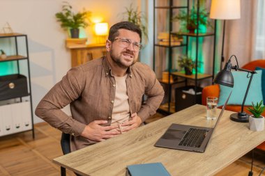 Hayal kırıklığına uğramış, Kafkas erkek, ofis bilgisayarında çalışırken aşırı yemek yiyor. Sinirli iş adamı karın ağrısına dokunuyor ve rahatsızlık ve keskin bir ağrı hissediyor..