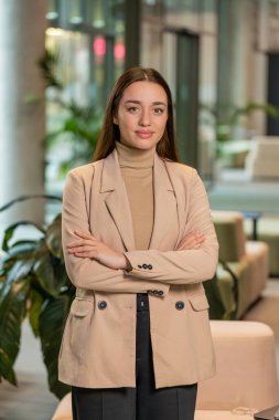 Kendine güvenen, resmi giyinmiş, kameraya bakan kadın patron. Güzel kadın ofis çalışanı modern ofis lobisinde mutlu ve kollarını kavuşturmuş duruyor. İş adamları portreleri