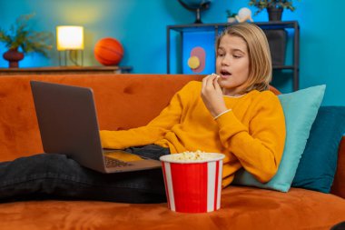 Beyaz çocuk evde dizüstü bilgisayardan film izlemekten hoşlanıyor. Patlamış mısır çiğner, komik sahnelerde güler, kanepede rahat bir şekilde yatarken karnına sarılır, oturma odasında eğlenir.