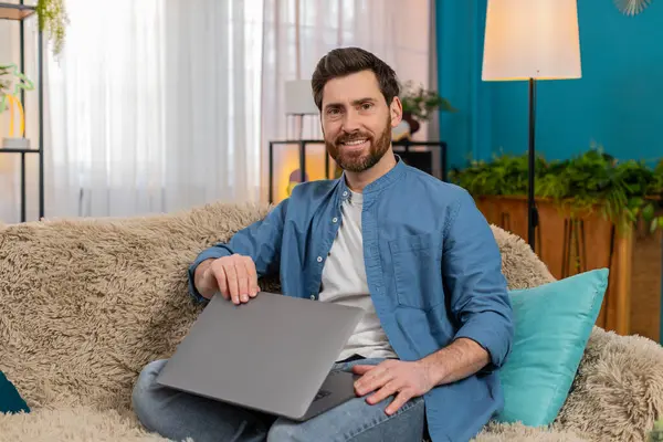 Evdeki genç adam işini bitirdikten sonra bilgisayarını kapatırken memnuniyetle gülümsüyor. Kanepede oturan beyaz adam kendini başarılı, rahatlamış ve projelerini tamamlamaktan mutlu hissediyor.