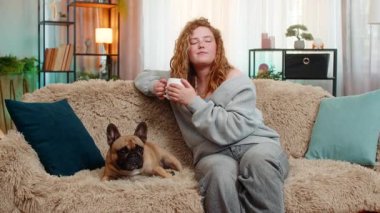Genç, mutlu, Kafkasyalı, kızıl saçlı kadın sıcak kahve içiyor. Huzurlu bir sabah anı yaşıyor. Pug dog onun yanında sessizce oturur, sükunet, samimiyet ve duygusal bir bağ yaratır.