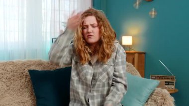 Evde genç bir kadın hayal kırıklığı ve duygusal hayal kırıklığı gösteren facepalm jestleri yapıyor. Kanepedeki beyaz saçlı kız üzgün, hata sonucu cesareti kırılmış, problem ya da beklenmeyen kötü sonuç.