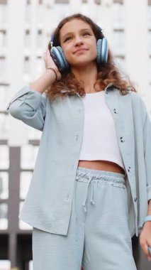 Kablosuz kulaklıklı, neşeli, çocukluk çağındaki çocuk dışarıda dans eden enerjik disko rock 'n roll müziği dinliyor. Kentsel Avrupa şehir sokaklarında yürüyen bir kız