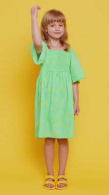 Gibi. Çocukluk çağındaki mutlu çocuk kameraya olumlu bakıyor olumlu bir şey işaret ediyor, olumlu bir geri bildirim harika bir haber. Sarı arka planda izole edilmiş çocuklar. Dikey