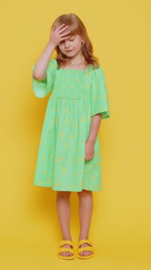 Avuç içi. Yazıklar olsun sana. Üzgün, sarışın kız çocuğu avuç içi hareketi yapıyor. Sıkılmış, hayal kırıklığına uğramış, kötü haber. Sarı arka planda izole edilmiş küçük çocuklar. Dikey