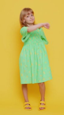 Saldırgan kızgın genç kız kameraya karşı dövüşmeye çalışıyor, yumruklarını sallıyor, ifadeyle boks yapıyor, cezalandırıyor, taciz ediyor, öfkeleniyor. Stüdyonun sarı arka planında izole edilmiş kabadayı çocuk. Dikey