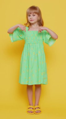 Küçük sarışın kız çocuğu reklam için aşağıdaki fotokopi alanını işaret ediyor, sosyal medya uygulamasını takip ediyor, evlenme teklifi duyurusu öneriyor. Küçük reşit olmayan çocuklar. Dikey