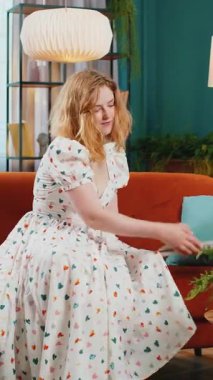 Serbest çalışan kadın dizüstü bilgisayarı açıyor, not defteriyle eğitime başlıyor, mesajlar gönderiyor, online alışverişler yapıyor, evdeki oturma odasında film izliyor. Kanepede oturan kızıl saçlı kız. Dikey