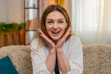 Orta yaşlı bir kadın evdeki koltukta kameraya şaşkınlıkla bakıyor, vay canına diyor ve büyük bir heyecanla tepki veriyor. Genç bir kız, beklenmedik bir an ya da haberle şaşkına dönmüş bir şekilde şaşkınlık ve görünür bir şok yaşıyor..