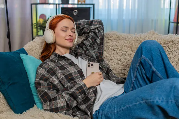 Evde gözleri kapalı sesli kitap dinleyen genç bir kadın zihninde huzurlu bir şekilde hikaye sahneleri canlandırıyor. Kafkasyalı kızıl saçlı kız koltukta, sakin anın tadını çıkarıyor, ses, ses ve hayal gücüne odaklanmış.