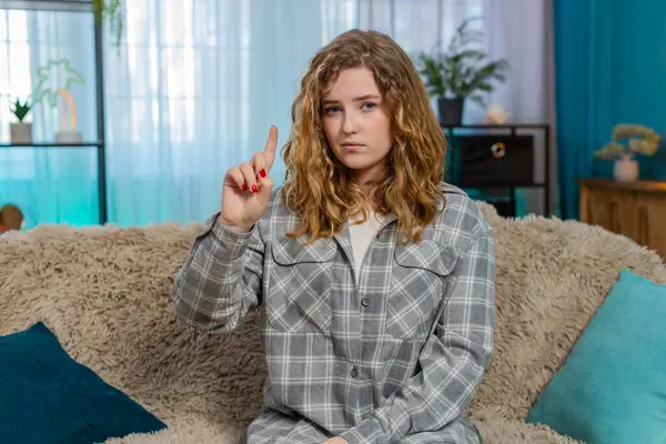 Evde el sallayan genç bir kadın ciddi bir yüz ifadesi ile fikir ya da öneriyi reddediyor. Kanepede oturan beyaz saçlı kız reddediyor, duygusal tepki veriyor, güçlü bir kişisel konumu var.