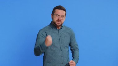 Hayal kırıklığına uğramış, orta yaşlı, gözlüklü, kızgın bir ifadeyle el kaldıran, kavga eden, çatışma nedenini soran orta yaşlı bir adam. Neden bu kadar inatçısın? Yetişkin adam mavi arkaplanda izole edildi