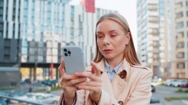 Kafkasyalı yetişkin iş kadını cep telefonuyla internette sohbet ediyor mutlu bir orta yaşlı kız cep telefonu kullanıyor, şehir merkezindeki caddede SMS ile iletişim kuruyor..