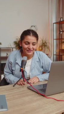 Mutlu blogcu kadın podcast yapıyor, atölye çalışması yapıyor, webinar yapıyor. Genç Hintli kız sözü geçen mikrofon ve laptop webcam 'de konuşuyor, video görüşmesi yapıyor, ev ofisini tartışıyor. Dikey