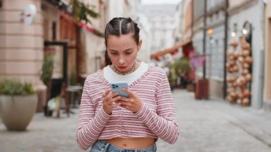 Akıllı telefon daktilosu kullanan genç bir kadın aniden piyango şokunu kaybeder. Kötü haber kaybı uygulaması başarısız virüs hırsızlığı. Şehir sokağında duran üzgün turist kız..