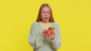 Üzgün, beyaz bir kadın akıllı telefon daktilo kullanıyor, oyun oynuyor, kaybediyor, piyango sonuçlarına şaşırıyor kötü şans kaybı şanssız haber. Sarı arka planda oldukça çekici bir kız.