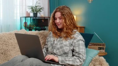 Genç bir kadın, uzun ve verimli bir çalışmanın ardından bilgisayarını kapatırken esneme ve esneme hareketleri yapıyor. Kanepede gülümseyen, yorgun ama sonuçtan ve kişisel başarıdan memnun beyaz saçlı bir kız..