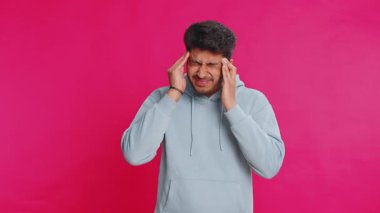 Memnun olmayan Hintli Hintli adam baş ağrısı problemini tedavi etmek için tapınakları ovuyor, tansiyon, migren, stres, ekşitme, acı içinde kıvranıyor, pembe arka planda yalnız başına izole edilmiş yüksek tansiyon