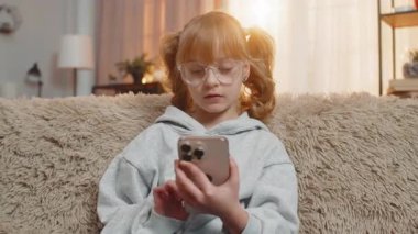 Genç bir kız akıllı telefondan gelen kötü haberlere üzgün bir şekilde tepki veriyor. Kanepede oturan beyaz çocuk maçı kaybettikten ya da kötü haber aldıktan sonra hayal kırıklığını yansıtıyor.