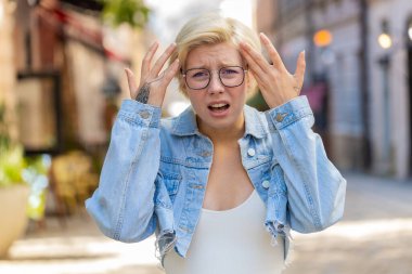 Hayal kırıklığına uğramış, omuz silken, üzgün, genç, sarışın bir kadın. Cevap vermiyor. Tepkisi belirsiz..