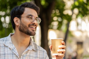 Mutlu Hintli adam sabah kahvesinin tadını çıkarıyor sıcak içecek ve gülümsüyor. Dinleniyorum, ara veriyorum. Şehir merkezindeki caddede dikilen Latin kökenli genç adam kahve içiyor. Dışarıdaki kasaba yaşam tarzları.