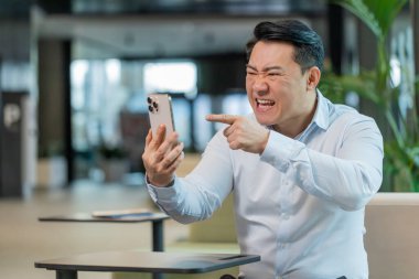 Kızgın genç patron, ofiste modern işyerinde otururken akıllı telefon kullanarak video konuşması üzerine tartışıyor. Tişörtlü, tatminsiz Çinli adam yöneticisi astlarına şirket sorunlarını anlatıyor..