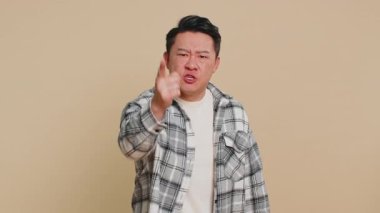 Tartışma. Hoşnut olmayan Asyalı bir adam, öfke ve hoşnutsuzlukla el kol hareketi yapıyor, başarısızlıktan dolayı azarlıyor, bunun neden olduğunu soruyor. Çinli orta yaşlı adam bej renkli stüdyo arka planında izole edilmiş.