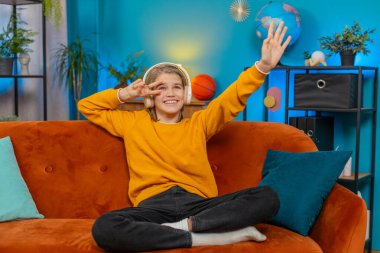 Kafkasyalı genç çocuk evde kablosuz kulaklıkla müzik dinliyor. Kanepede otururken, ellerle dans ederken, kafanızı sallarken, neşe ve coşku gösterirken, favori melodilerin tadını çıkarırken, dinlenirken,