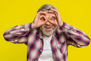 Olgun bir adam elleriyle dürbün şeklini alır, mesafeye bakar ve esprili dedektif yeteneğini ateşler. Sarı arka planda orta yaşlı bir adam el sallayan bir arkadaşı bekliyor.