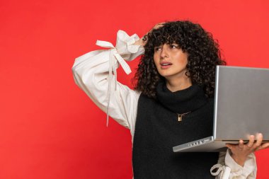 Kıvırcık saçlı hoşnutsuz bir kadın dizüstü bilgisayar kullanıyor. İnternette arama yapıyor. Ani piyangoyu kaybediyor. Kırmızı arka plandaki kız