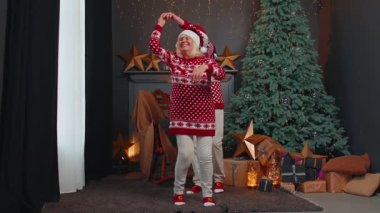 Kafkasyalı yaşlı çift büyükannesi süslü bir evde Noel ağacıyla dans ediyor. Yaşlı koca koca kutluyor, yılbaşı tatilinin tadını çıkarıyor.