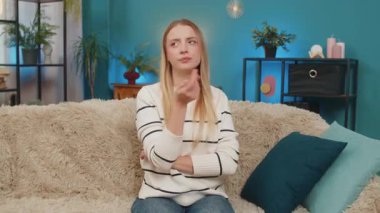 Kafkasyalı kadın kanepeye oturmuş, ani bir fikirden sonra gülümseyen bir sorun hakkında kafa yoruyor. Zafer için parmak kaldırma yaratıcı ilham rahatlaması. Yaşam tarzı neşeli duygu parlak zihin çözümü.