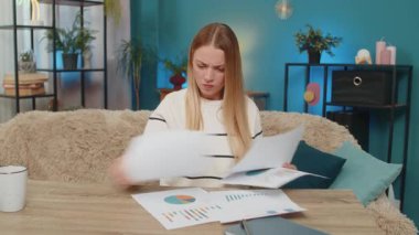 Dosyaları ve grafikleri gösteren belgeleri olan, fatura hataları ve iflasla uğraşan bir kadın. Kız hayal kırıklığına uğramış görünüyor, gergin bir şekilde dökülen kağıtlara dokunuyor, istatistiksel veriler, kaygılı finansal kayıplar.