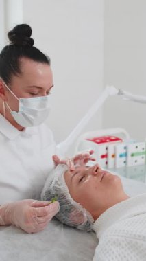 Kimyasal bir kadının yüzü soyulmuş. Güzellik uzmanı özel nemlendirici tıbbi asit kremi uyguluyor. Yüz bakımı yaşlanmayı önleyen kozmetik masaj prosedürü. Cilt esnekliğinin korunması