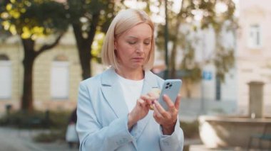 Hüsrana uğramış iş kadını, şehir caddesinde duran cep telefonundan kredi kartını kontrol ederken dolandırıcılığı keşfetti. Üzgün kadın işveren aldatma kurbanı oldu, hesabından para çalındı..