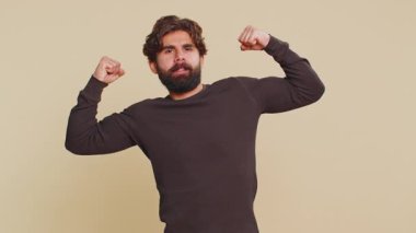 Güçlüyüm. Formda Lübnanlı adam kaslarını gösteriyor ve kendinden emin görünüyor, haklar için savaşma gücü hissediyor, başarı için enerji kazanıyor. Stüdyoda bej arka planda Hintli adam..