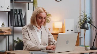 Diz üstü bilgisayara bakan sinirli olgun bir kadın, kötü düşük internet bağlantısından rahatsız olmuş, ofis evinde uzaktan çalışan stresli bayan zor iş ya da sistem çökmesi yüzünden mutsuz..