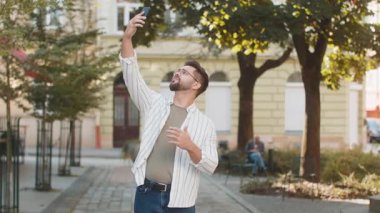 İletişim sinyalini yakalamaya çalışan genç bir turist, cep telefonundaki internet şehir sokaklarında daha iyi bir bağlantı için akıllı telefonu açtı. Hüsrana uğramış yetişkin erkek gezgin kasabada dikiliyor..