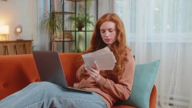 Kanepede dizüstü bilgisayarını kullanarak evrak işleriyle uğraşan beyaz, genç bir kadın. Günlük giysiler içinde üzgün bir kız. Evrakları netbook 'la havaya fırlatıyor ve evdeki oturma odasında ekrana bakıyor..