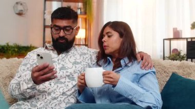 Hintli çift kanepede oturur, sabah kahvelerini içerler ve konuşurken sakince akıllı telefonlara bakarlar. Arap ailesi güne huzurlu bir şekilde başlayıp içeride haberleri tartışıyor.
