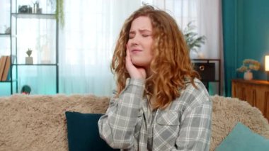 Güçlü diş ağrısı ve diş rahatsızlığından muzdarip, yanak ağrısı çeken genç bir kadın. Kanepede kendini kötü hisseden beyaz saçlı bir kız, üzgün bir ifade, keskin ağrıdan dolayı duygusal stres.