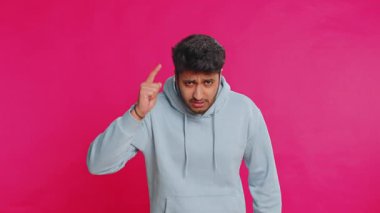 Tartışma. Rahatsız edici ve hoşnutsuzlukla el kol hareketi yapan genç Hintli adam başarısızlıktan dolayı azarlıyor, bunun neden olduğunu soruyor. İspanyol erkek, pembe stüdyo arka planında izole edilmiş..