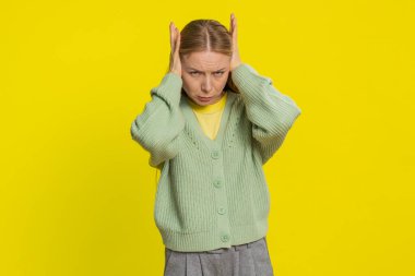 Duymak istemiyorum, dinle. Sinirli, sinirli, orta yaşlı, kulakları tıkayan, hayır diyen, tavsiyelerden kaçan, gürültülü sesleri görmezden gelen bir kadın. Sarı arka planda izole edilmiş yetişkin bir kız.