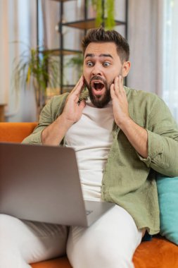 Kahverengi saçlı, dizüstü bilgisayar kullanan, postayla iyi haber mesajı alan sürpriz beyaz adam evinde online alışveriş yaparak piyango galibiyetini kutlarken şok oldu. Yaşam Tarzları.